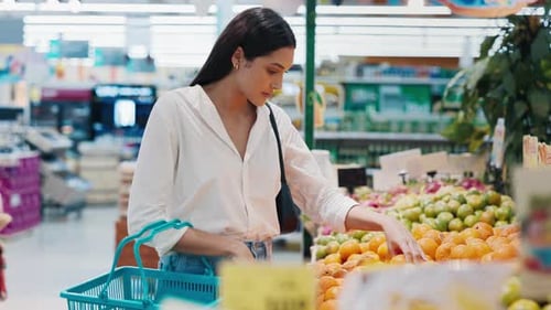 Beautiful Woman Standing In Supermarket By The Fruit Stand Selecting Oranges
