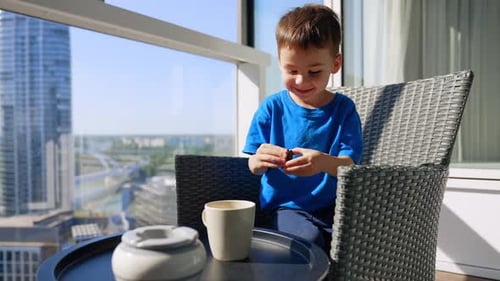 Little Boy Enjoying Cookie on Apartment Balcony