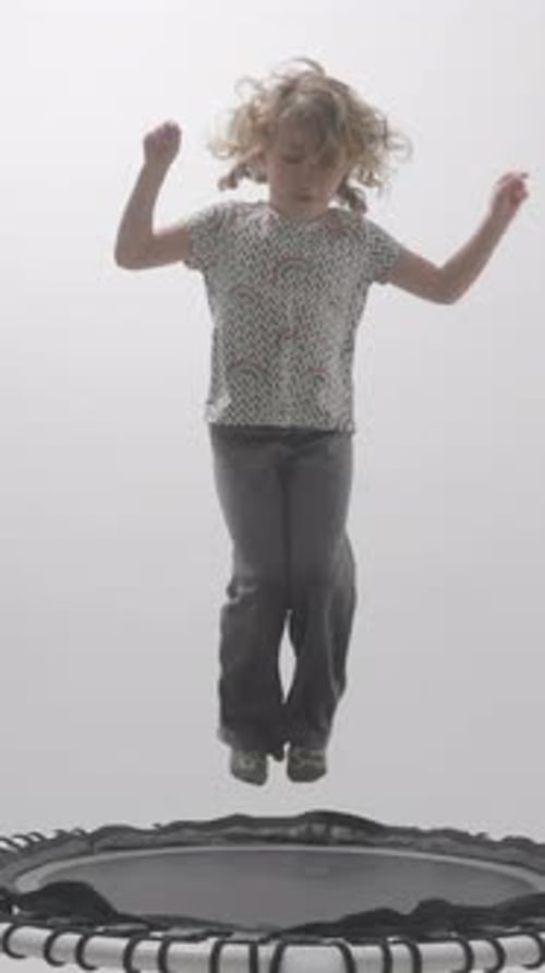 Energetic Child Leaps on Trampoline Indoors