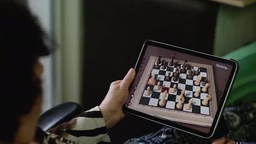 Femme âgée se concentrant sur le jeu d'échecs sur tablette