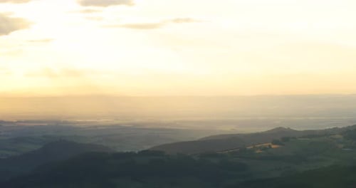 View of a mountainous landscape in the fog during sunset The golden colors of the hills are all over