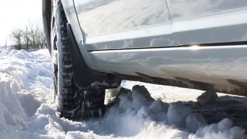 Car with winter tires riding on snowy road outdoors, closeup