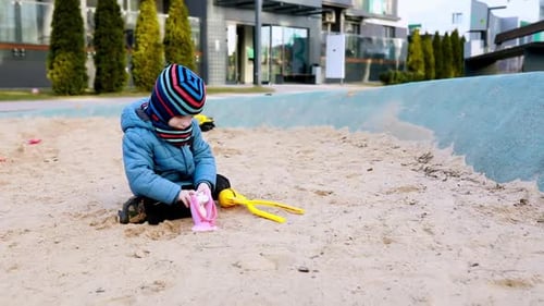 Child Plays in Sandbox at Modern Playground on Sunny Afternoon in Urban Setting