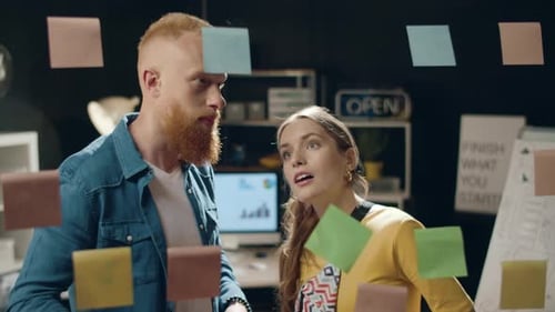 Young Businesswoman Discussing Innovative Ideas with Male Colleague in Hipster Office. Startup