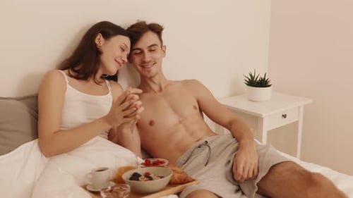 Romantic Couple Enjoying Breakfast in Bed Together