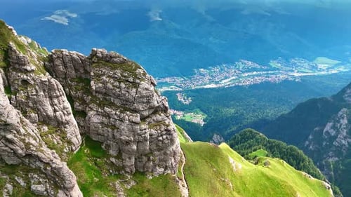 Steep rocks covered with green grass. Drone footage in the Bucegi Mountains, Romania.