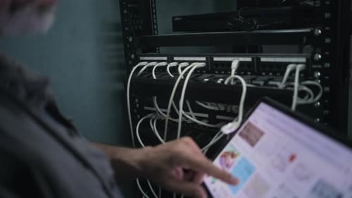 Männlicher Netzwerkadministrator arbeitet im Serverraum mit Tablet-Computer