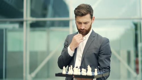 Porträt eines erfolgreichen, seriösen Geschäftsmannes, der ein Brett mit Schach in der Hand hält, bietet an, anzunehmen
