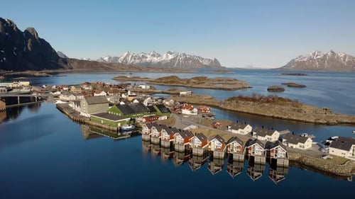 Aerial drone shot of cottages in Lofoten Norway with big mountains in the background. surrounded by