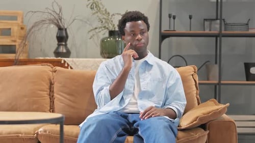 Man Sitting Indoors Contemplating Something on Couch