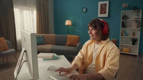 Young Adult Typing on Computer With Headphones