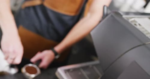 Caucasian male barista with apron preparing coffee for coffee machine in cafe