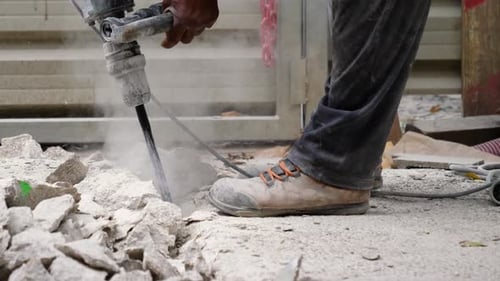 Construction Worker Handling Pneumatic Hammer Breaking Concrete Ground, Slow Motion, Close Up