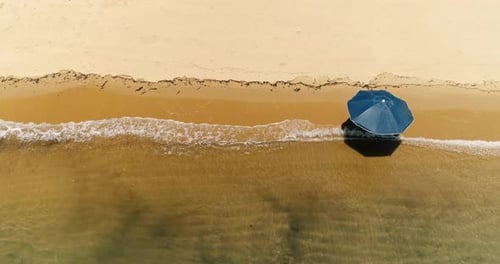 Aerial top down drone view of lonely sun umbrella in a deserted orange sand beach