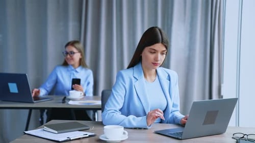 Women work in the office sitting at the computers. Brunette lady is excited and happy.