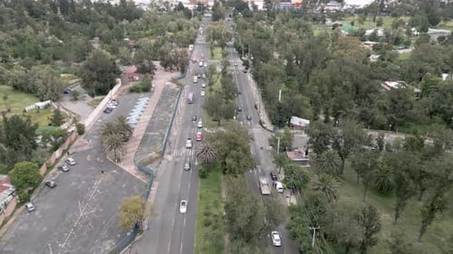 Toma aérea de un Zumbido desde adelante sobre el tráfico urbano con árboles y casas en las zonas urbanas de México — Día nublado