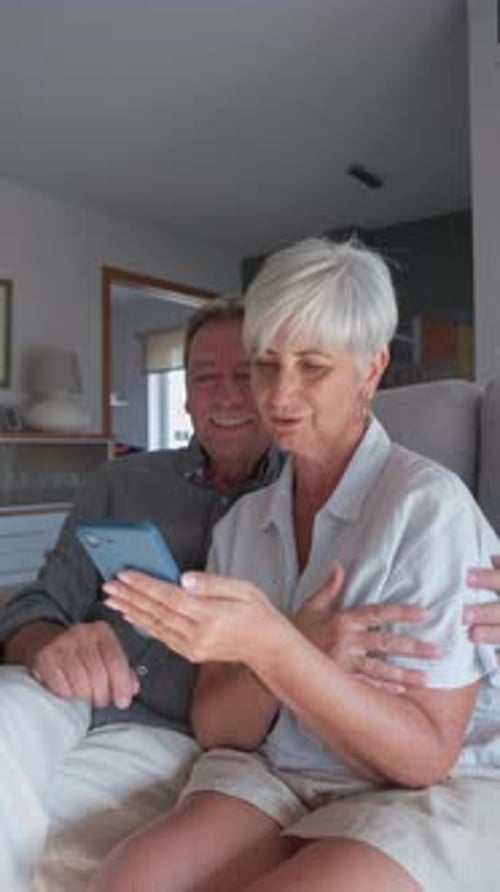 Senior Couple Relaxing on Sofa Watching Smartphone