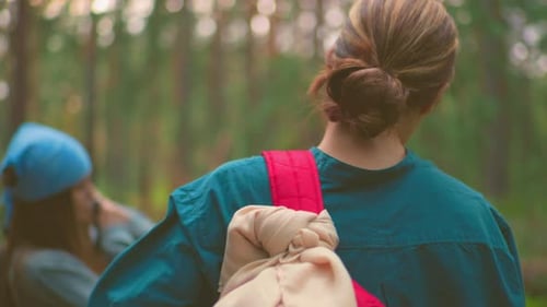 Back View of Hikers Hanging Bags Over Shoulders in Serene Forest