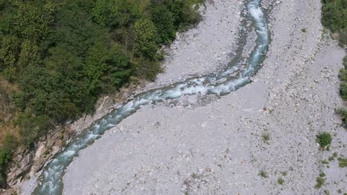 Die Luftaufnahme zeigt einen ruhigen Fluss, der sich durch ein felsiges, trockenes Tal schlängelt, das von Lu umgeben ist