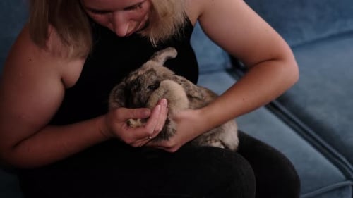 Woman Holding Rabbit on Lap Inside Home