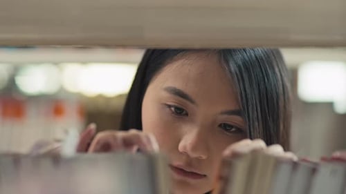 Female Student Looking for Needed Book in Library