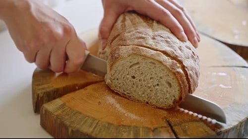 Slicing Fresh Rye Bread on Wooden Board