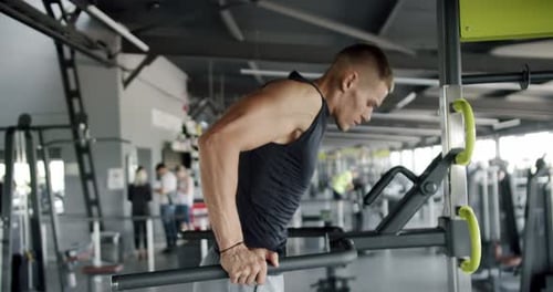 Focused Young Man Doing Dips at a Modern Gym Environment