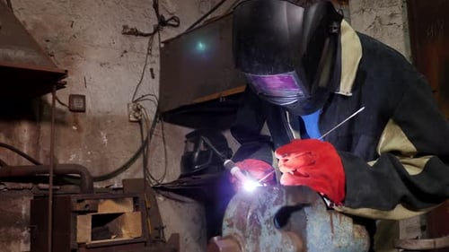 A Handyman Performs Welding and Grinding at His Workplace in the Workshop