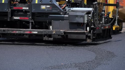 Asphalt Paving Machine Laying Fresh Blacktop on a Road Hot Asphalt is Being Evenly Spread Across the