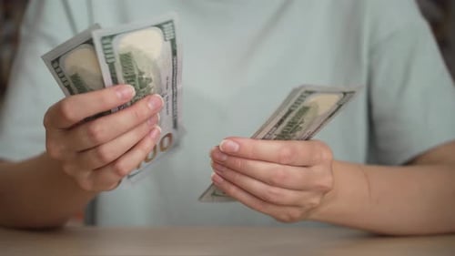 Hands Counting Stack of One Hundred Dollar Bills