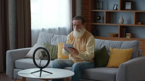 Senior Man Using Tablet With Ring Light Indoors