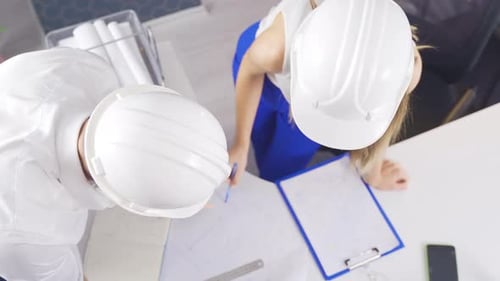 Engineers Reviewing Blueprints at White Desk