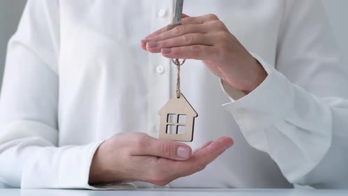 Hands Protecting Keychain Shaped House Home and Real Estate Property Insurance