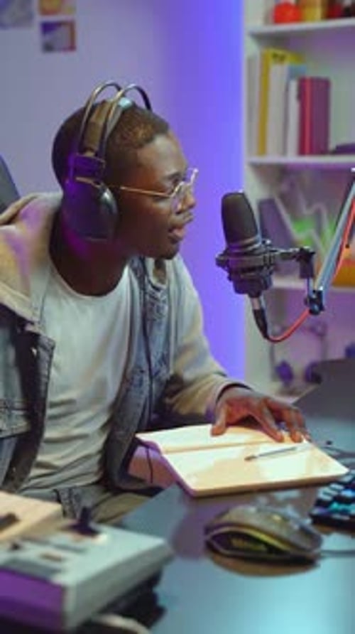 Man Speaking Into Microphone With Headphones At Desk