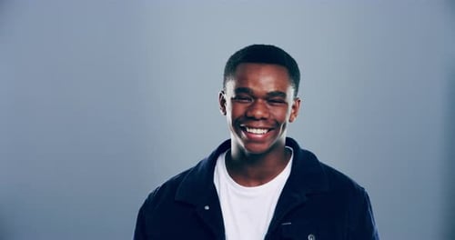 4k video footage of a young man laughing against a grey studio background