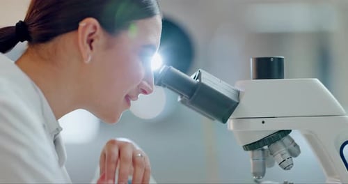 Female Scientist Using Microscope in Bright Lab