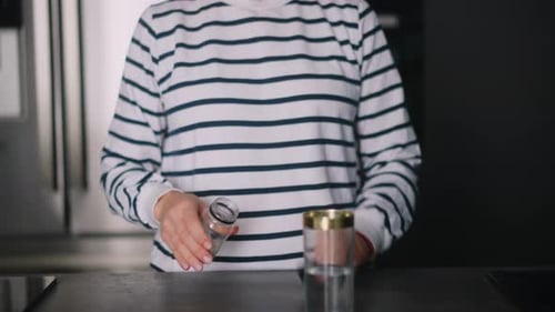 Close Up Footage of Young Woman Taking Pills with a Glass of Water at Modern Kitchen Curly Blonde