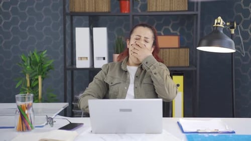 Sleepy business woman yawns looking at camera.
