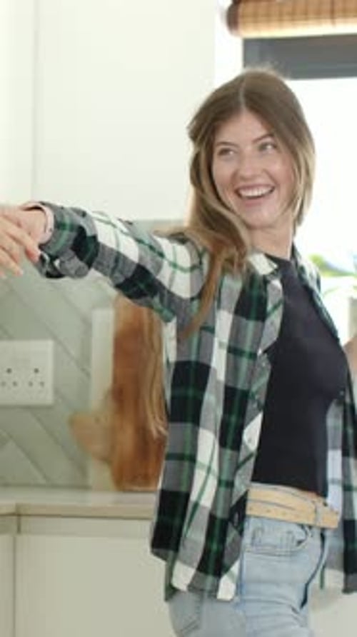 Vídeo vertical: estendendo uma mulher em camisa xadrez girando, segurando a mão com um amigo entrando na cozinha