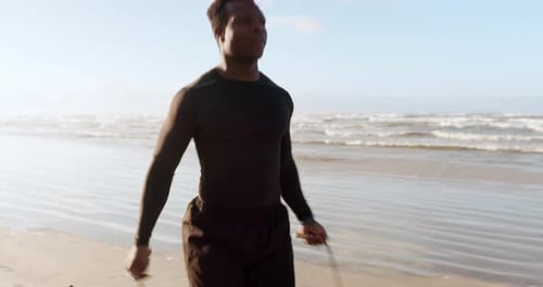 Black man, fitness and skipping rope on beach in cardio exercise, workout