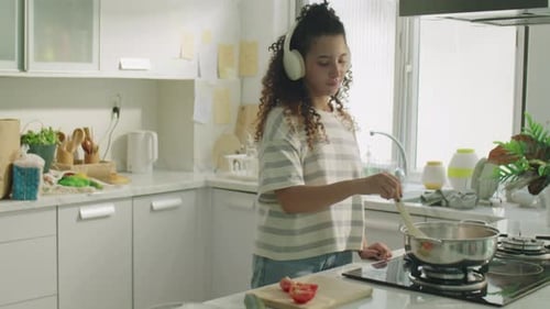 Woman Cooking Food in Kitchen with Headphones On