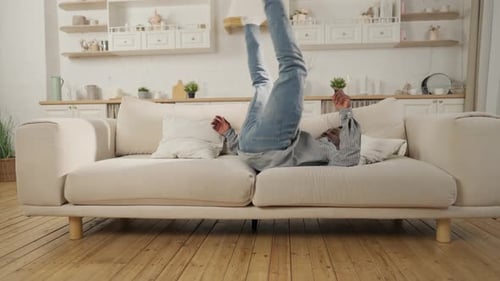 Joy of Weekend and Vacation Black Man Falling on Couch in Apartment Slow Motion Carefree Young