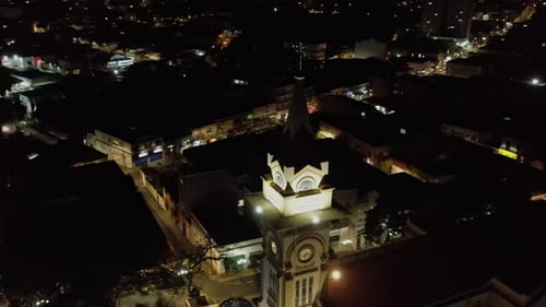 Vue aérienne incroyable d'une ville la nuit. Drone tournant autour du clocher d'une église.