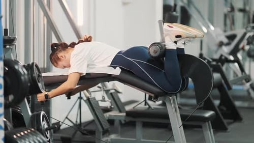 Determined Woman Training Hamstrings on Leg Curl Machine