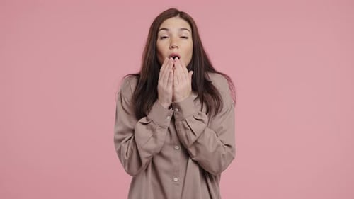 Woman Yawning Against a Pink Background