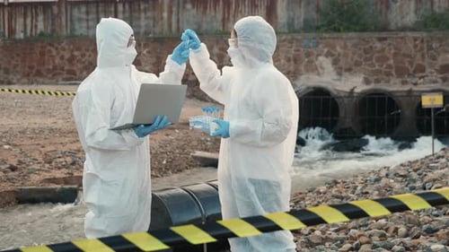 Ecologist Sampling Water From the River with Test Tube and Save Data to Laptop Computer
