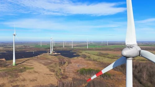 drone footage of wind turbines in a wind farm generating green electric energy on a wide green field