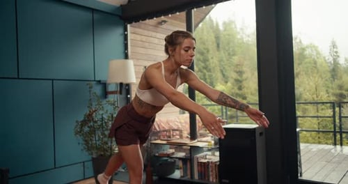 A Blonde Girl in a White Top with Tattoos Does Balance and Coordination Exercises on a Special Mat