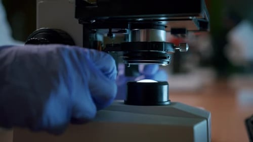 A young female scientist adjusts the professional microscope in the laboratory—a close-up shot of th