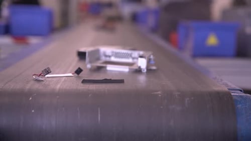 Nahaufnahme von Elektroschrott auf einem sich bewegenden Förderband in der Recyclinganlage. Metallisch